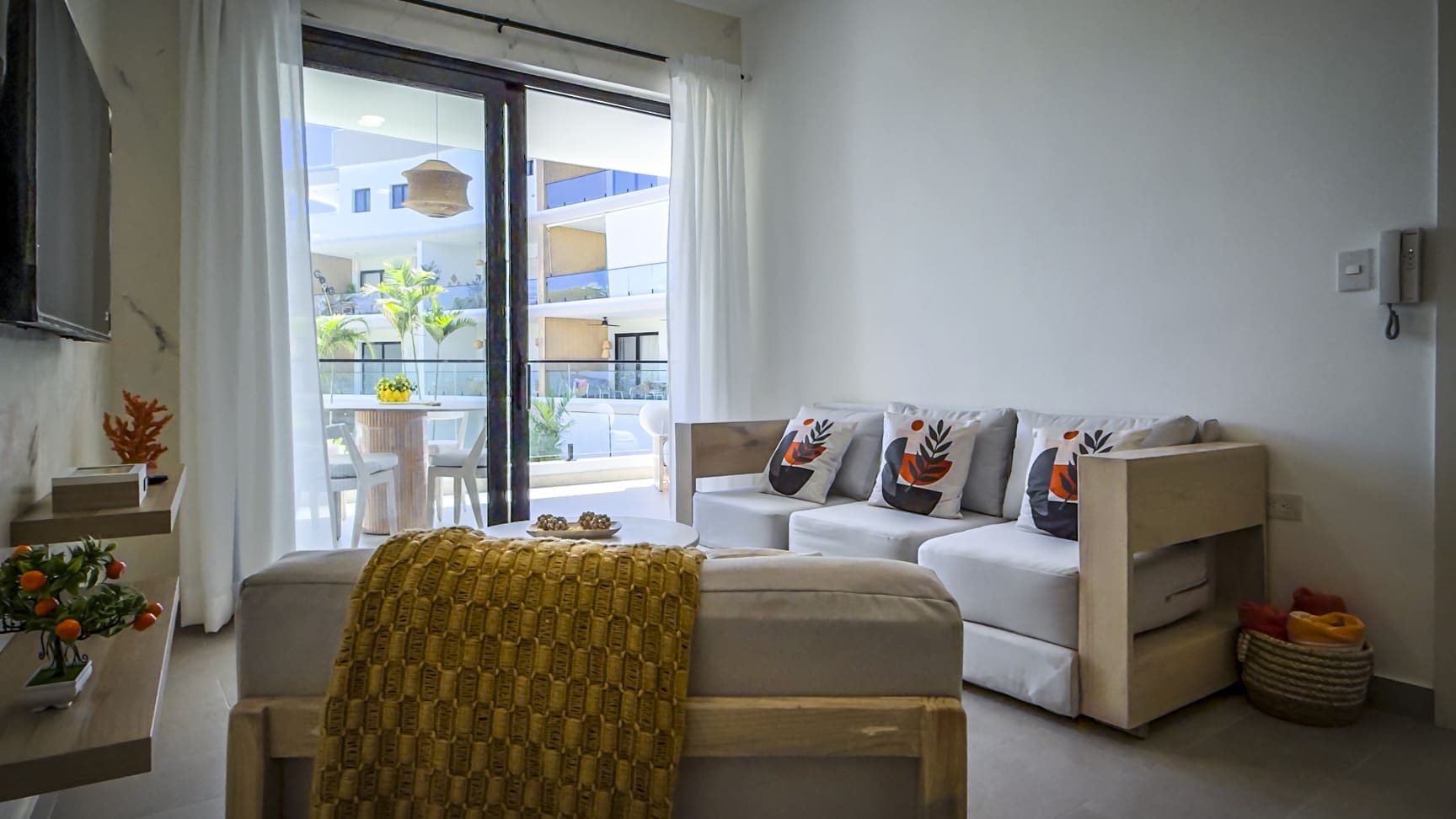 Bright living room with white sofa, yellow throw, and balcony view