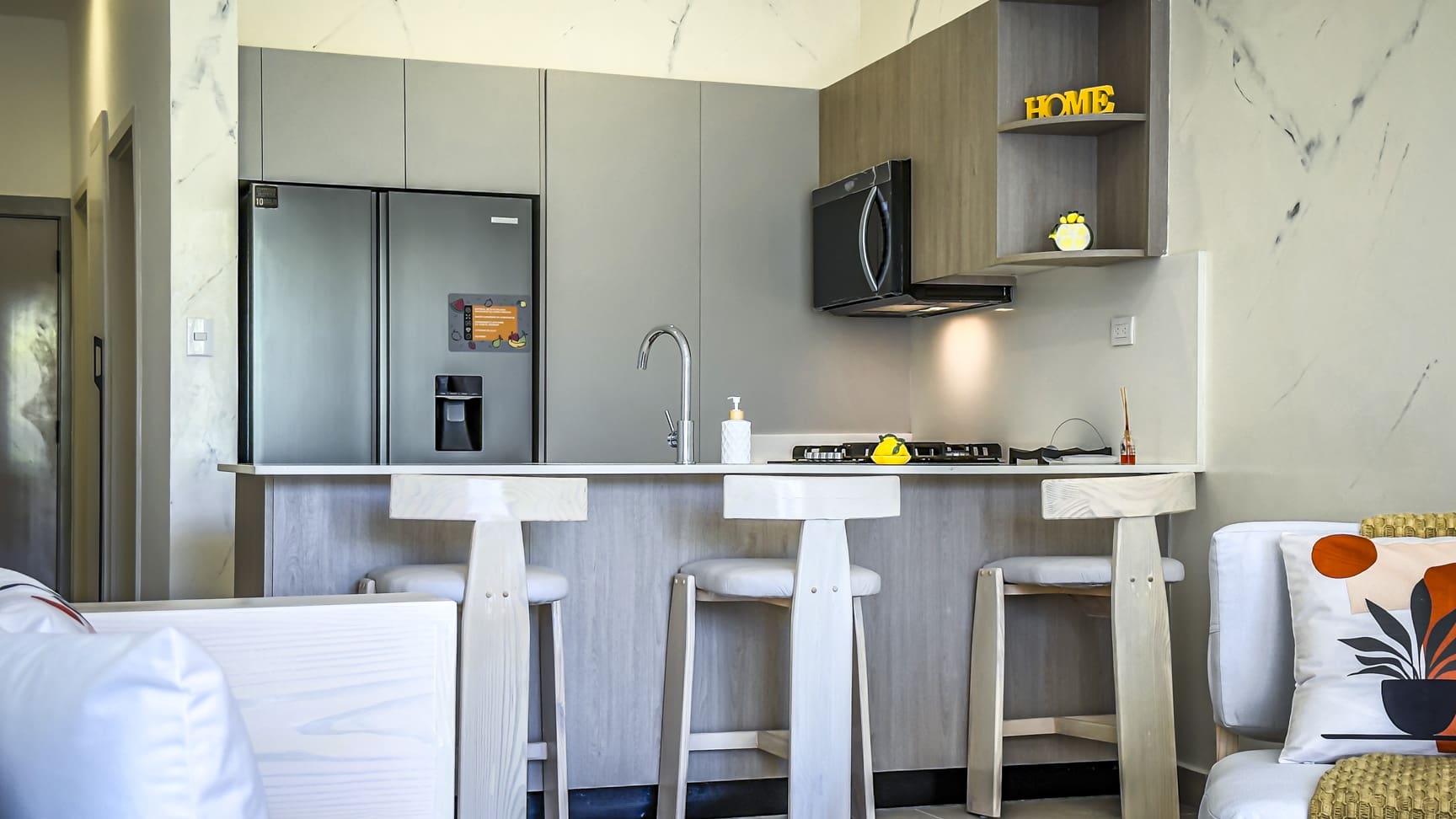 Modern kitchen with island, bar stools, and stainless steel refrigerator