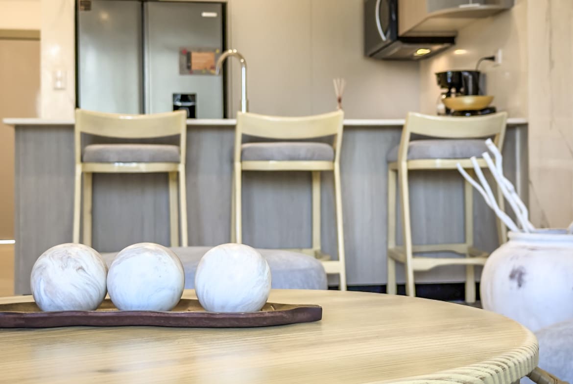 Modern kitchen island with bar stools and decorative spheres on a coffee table.