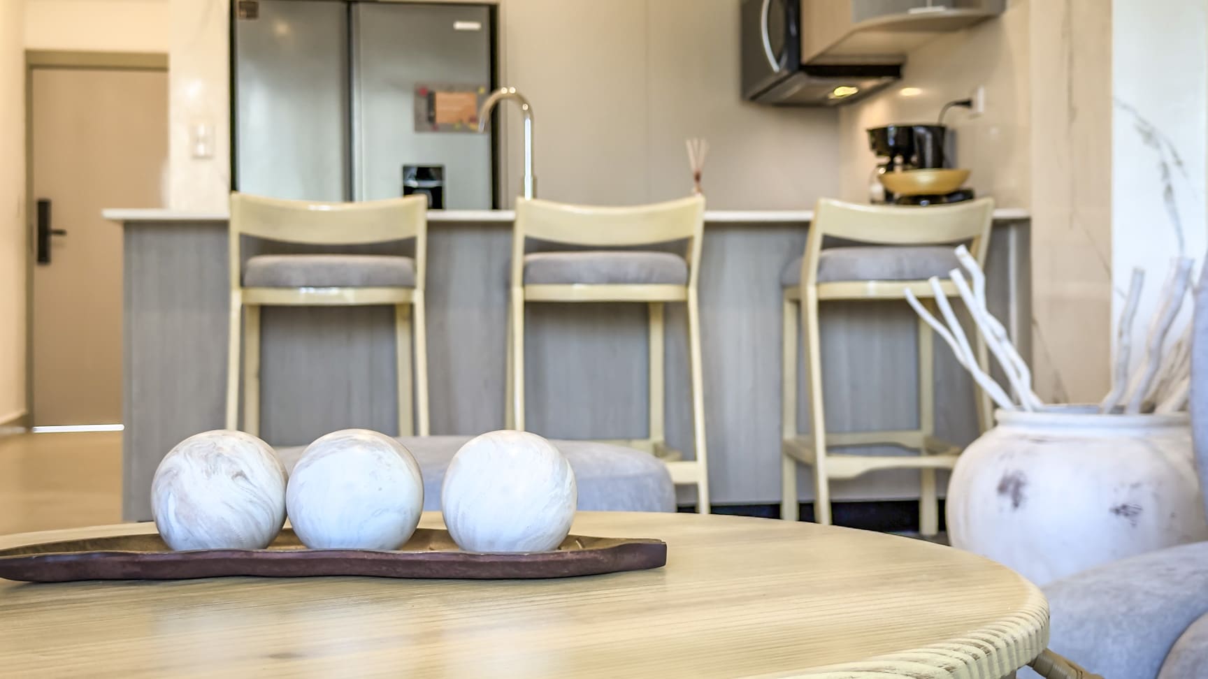 Modern kitchen island with bar stools and decorative spheres on a coffee table.