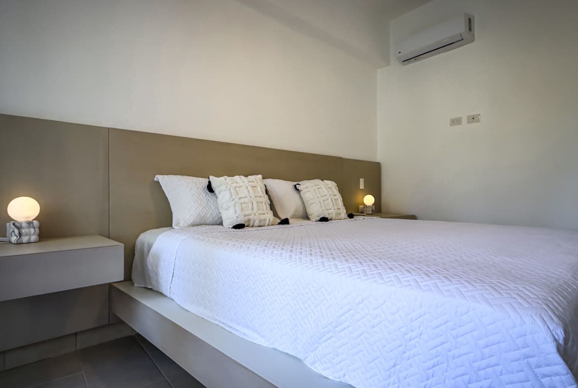 Modern bedroom with a king-size bed, white linens, and minimalist nightstands.