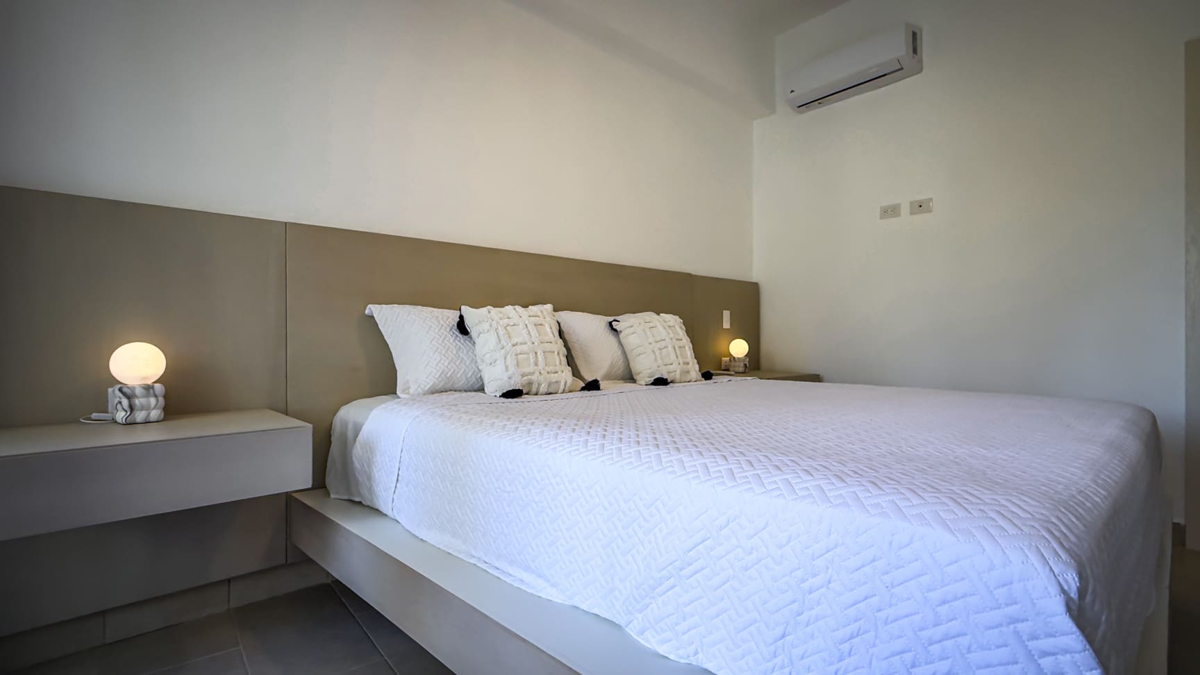 Modern bedroom with a king-size bed, white linens, and minimalist nightstands.