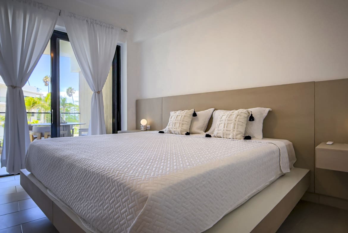 Modern bedroom with king-size bed, white linens, and balcony view