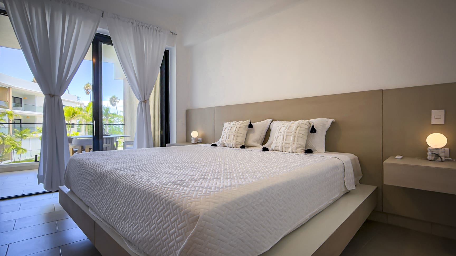Modern bedroom with king-size bed, white linens, and balcony view