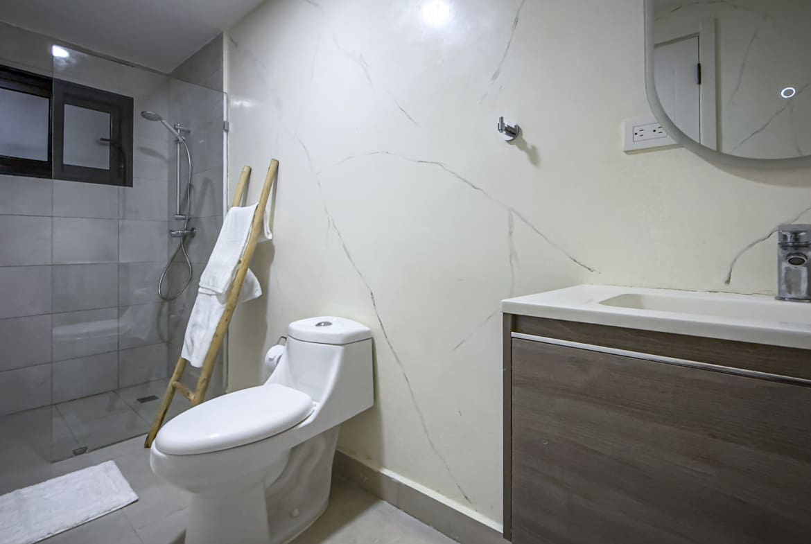Modern bathroom with white marble walls, a walk-in shower, and a wooden ladder towel rack.