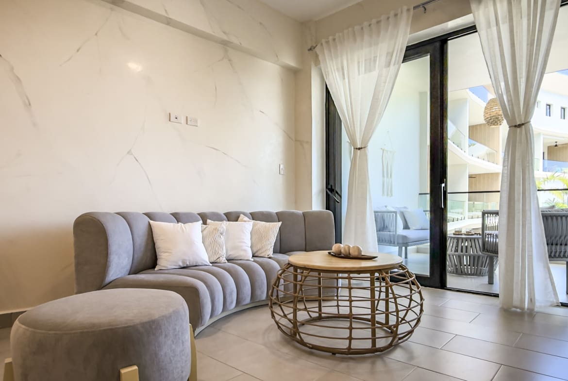Modern living room with curved grey sofa, round coffee table, and balcony view