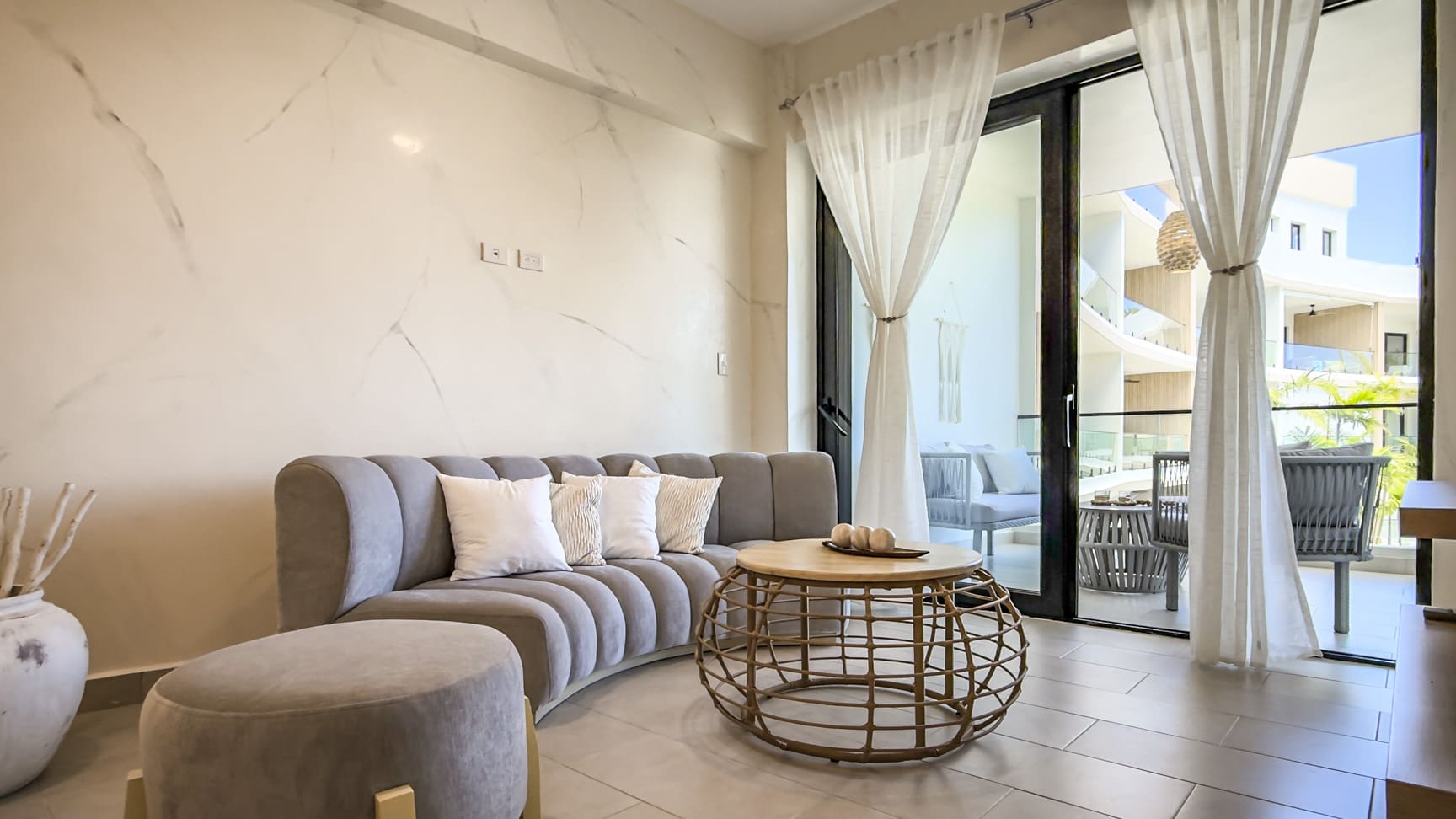 Modern living room with curved grey sofa, round coffee table, and balcony view