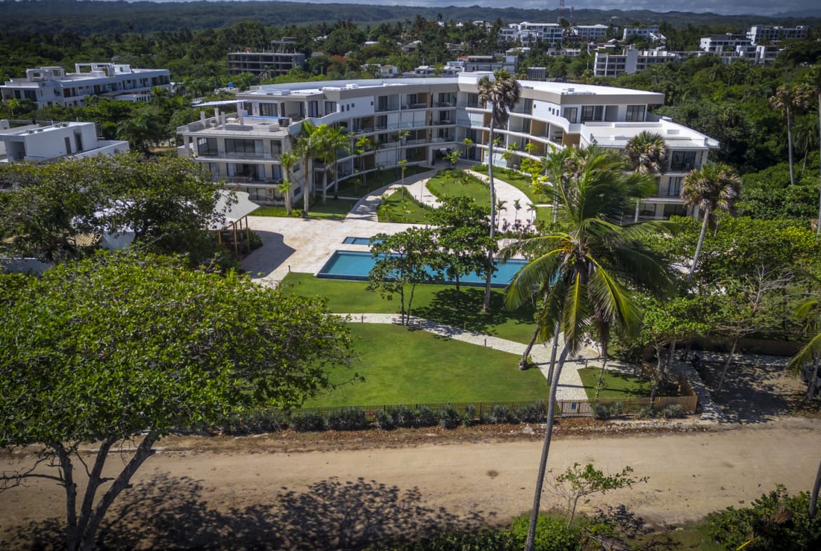 Aerial view of a modern resort with a swimming pool and palm trees.