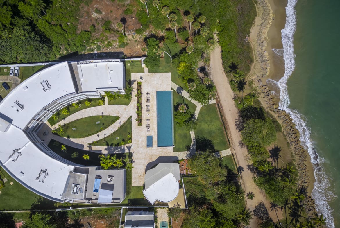Aerial view of a modern resort with a pool and beach access