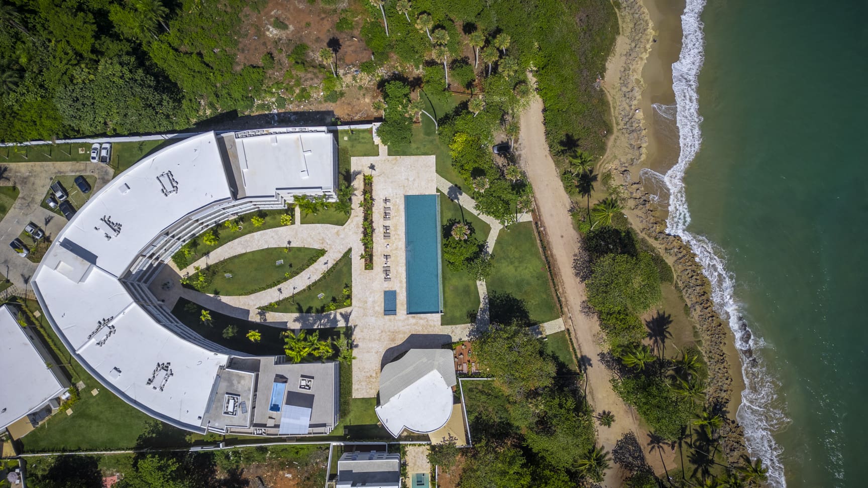 Aerial view of a modern resort with a pool and beach access