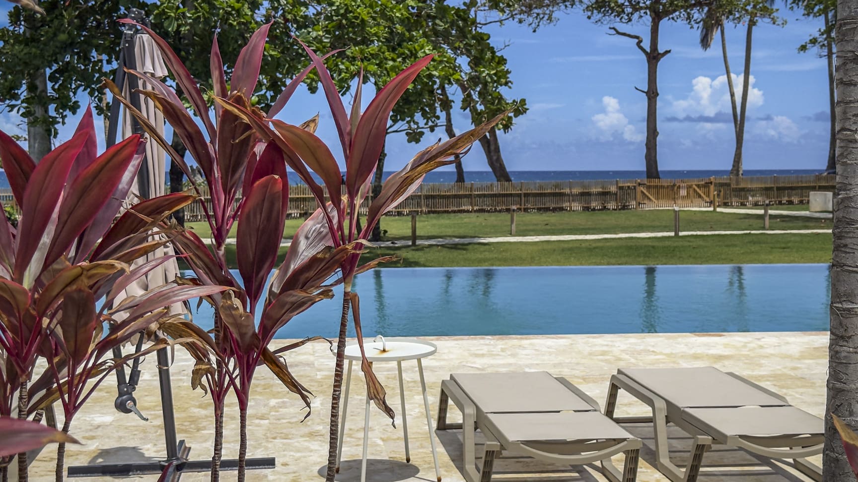 Tropical resort poolside with lounge chairs and ocean view
