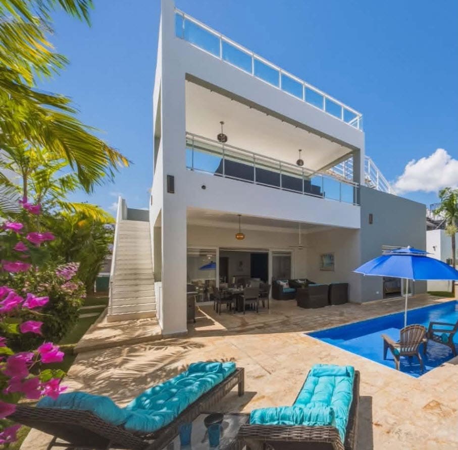 Luxury villa with private pool and lounge chairs in a tropical setting.