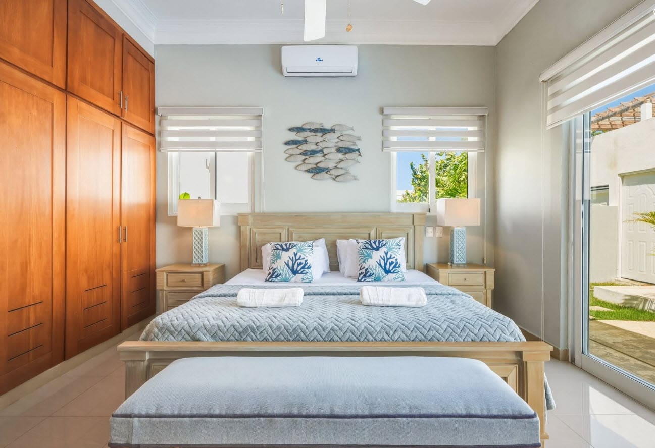Beach-themed bedroom with king-size bed, blue bedding, and fish wall art.