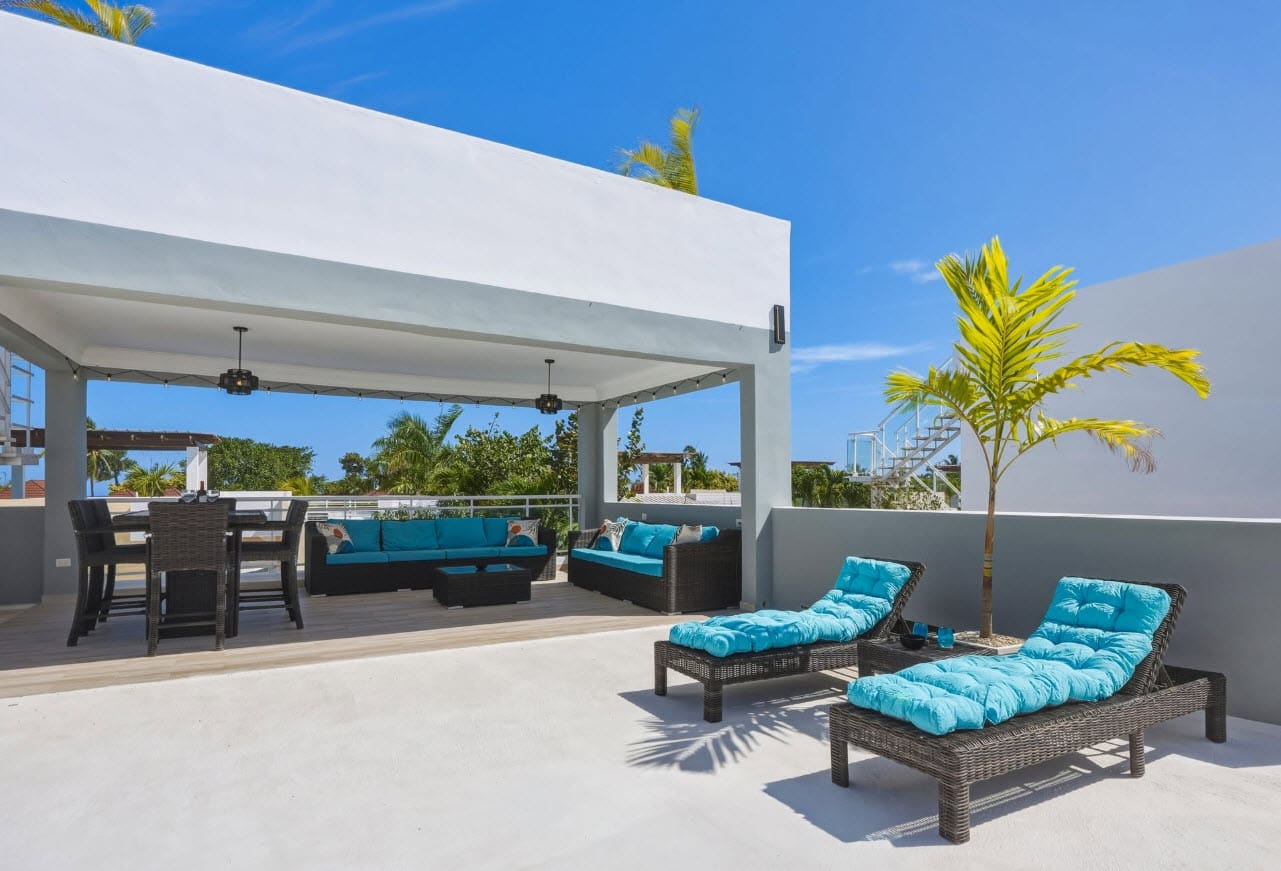 Modern rooftop patio with blue lounge chairs, wicker sofa, and dining set.