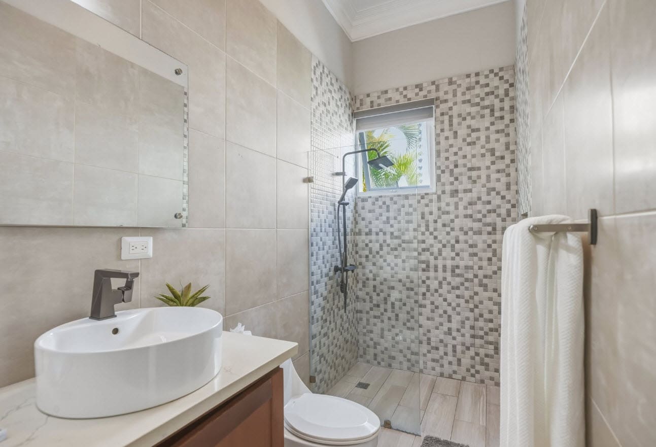 Modern bathroom with white sink, toilet, and tiled shower.