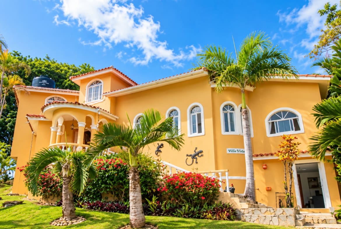 Yellow villa with palm trees and tropical flowers, "Villa Vista" sign