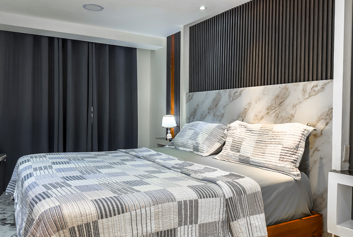 Modern bedroom with a king-size bed, marble headboard, and dark wood accent wall