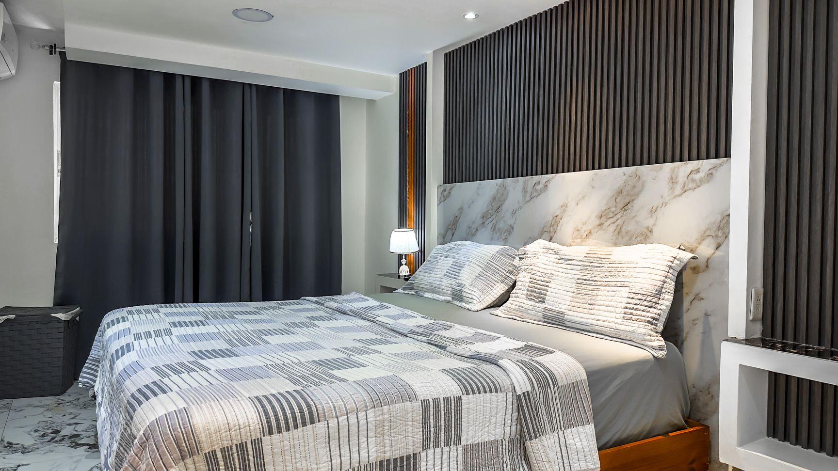 Modern bedroom with a king-size bed, marble headboard, and dark wood accent wall