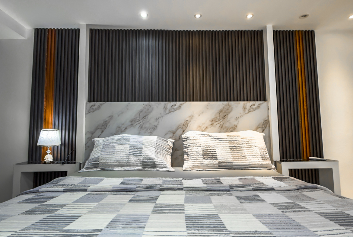 Modern bedroom with a king-size bed, marble headboard, and wood accent wall