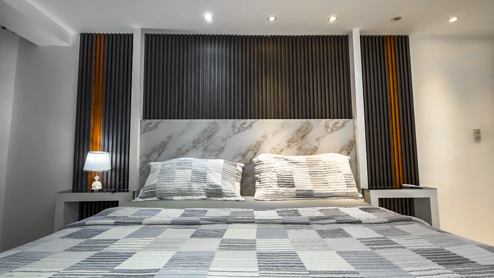 Modern bedroom with a king-size bed, marble headboard, and wood accent wall