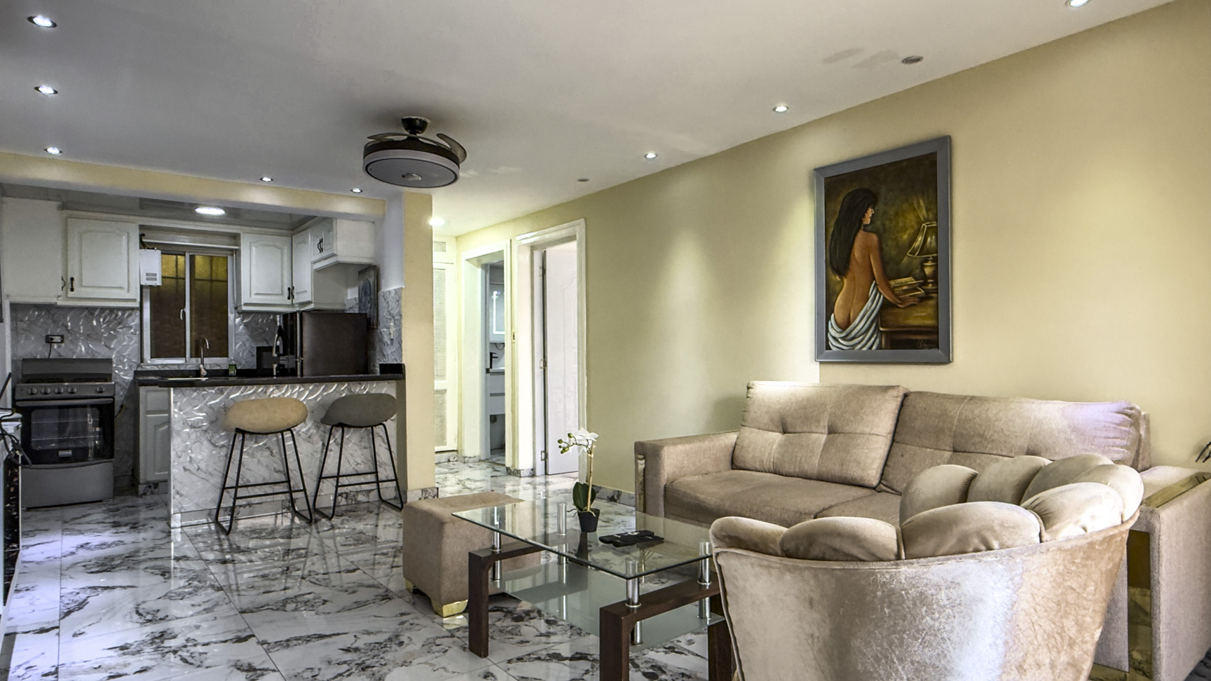 Modern living room and kitchen with plush seating and marble floors