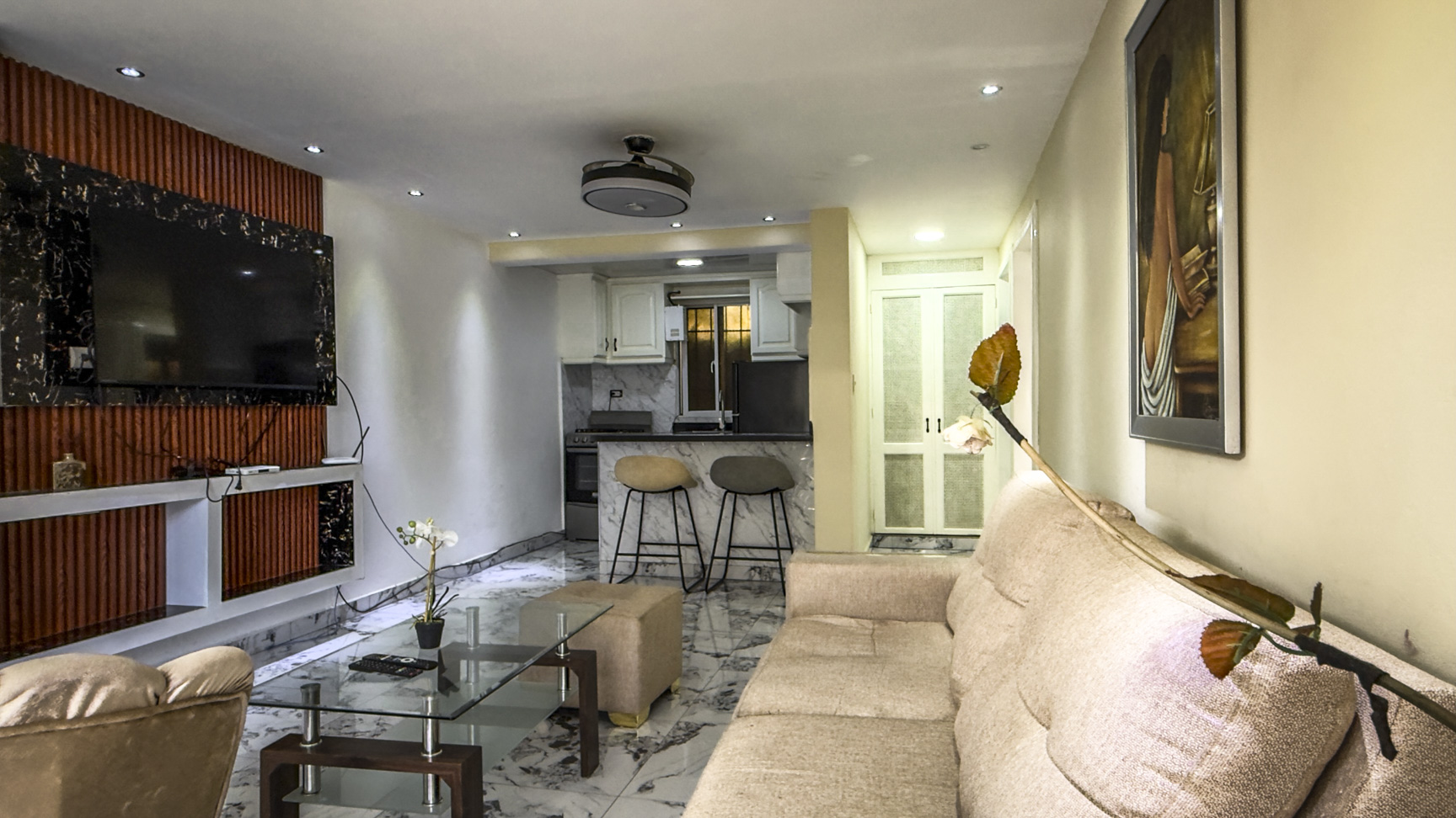 Modern living room with sofa, glass coffee table, and open-plan kitchen