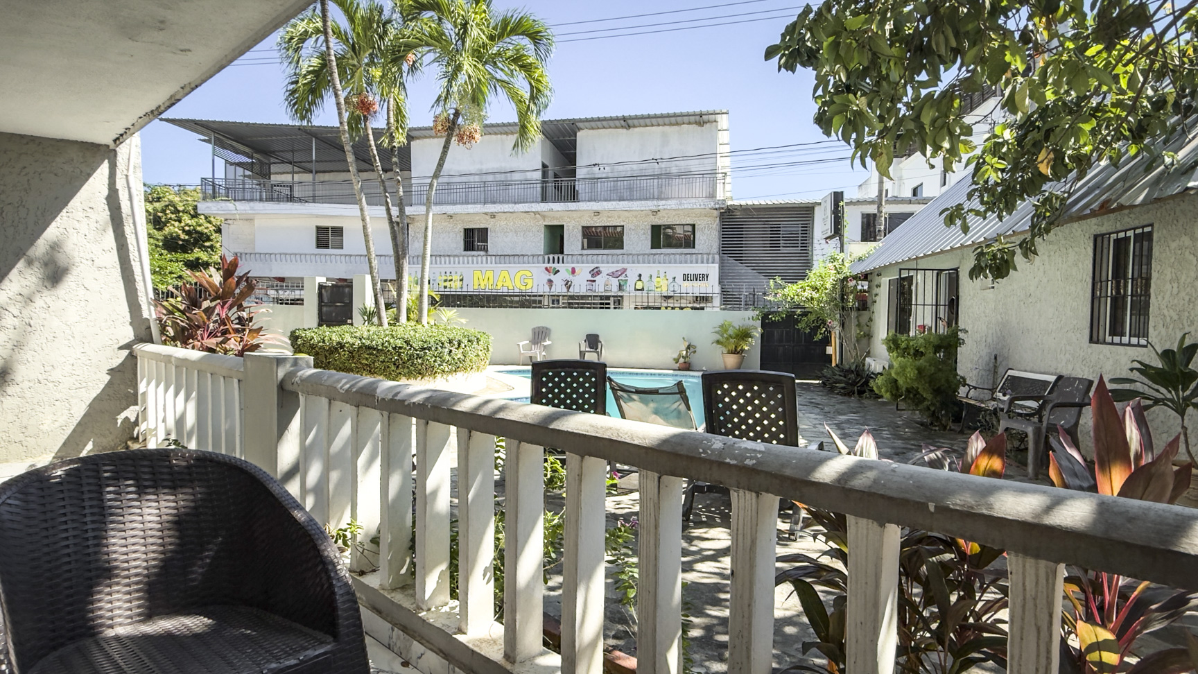 Courtyard with pool, chairs, and tropical plants outside a building.