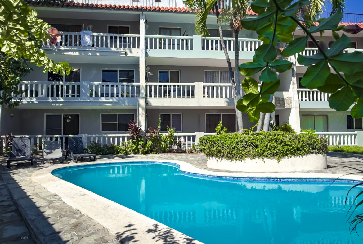 Tropical resort with swimming pool and balconies surrounded by lush greenery