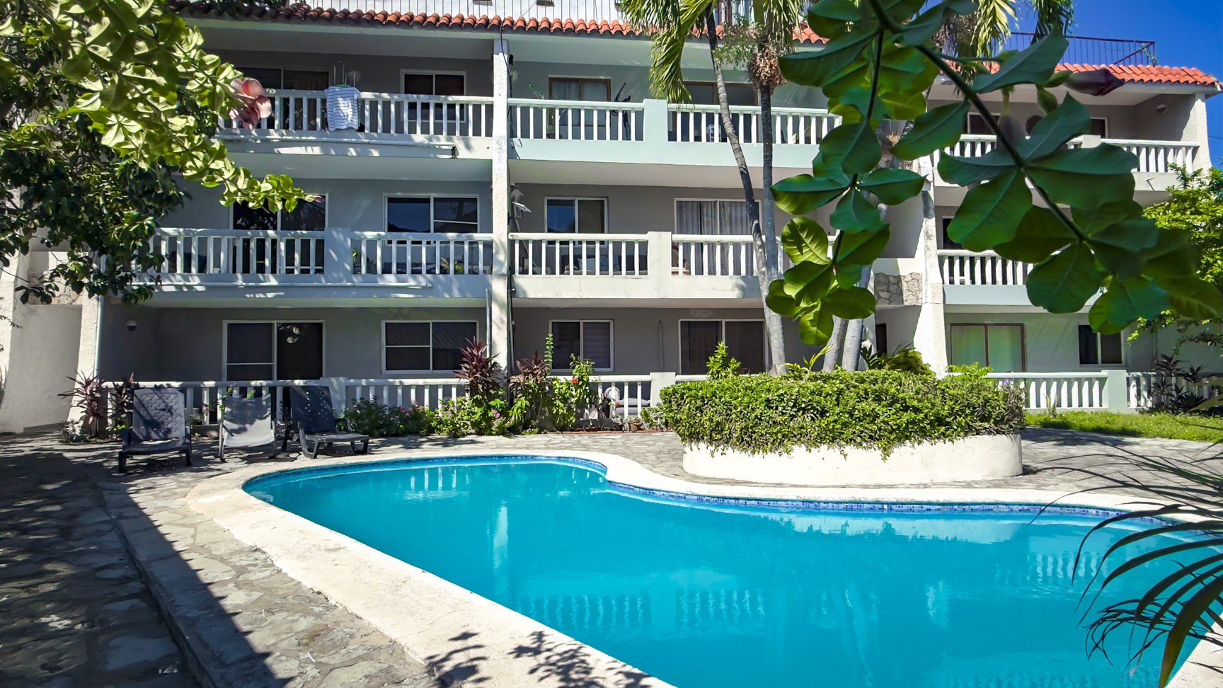 Tropical resort with swimming pool and balconies surrounded by lush greenery