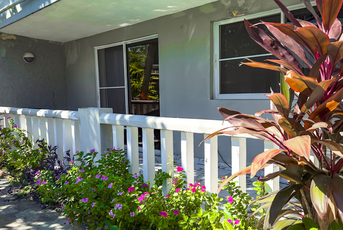 Tropical balcony with white railing, vibrant flowers, and lush foliage.