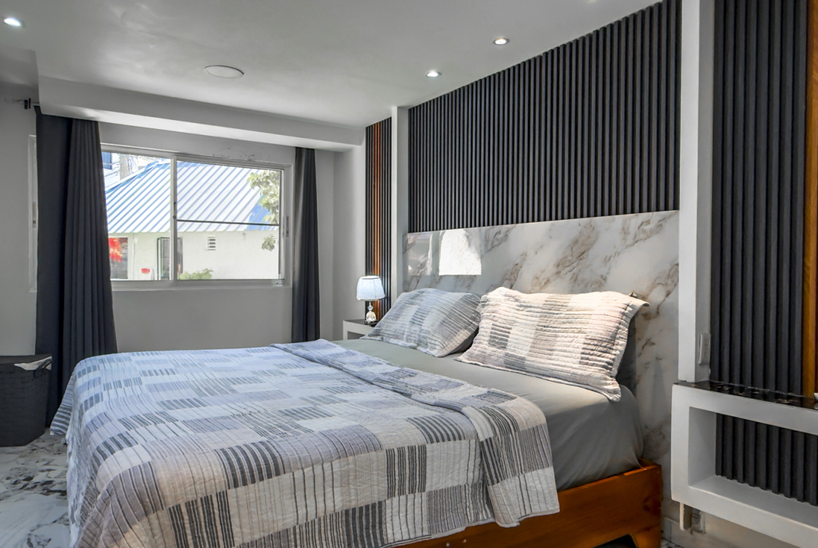 Modern bedroom with a king-size bed, marble accents, and a stylish headboard.