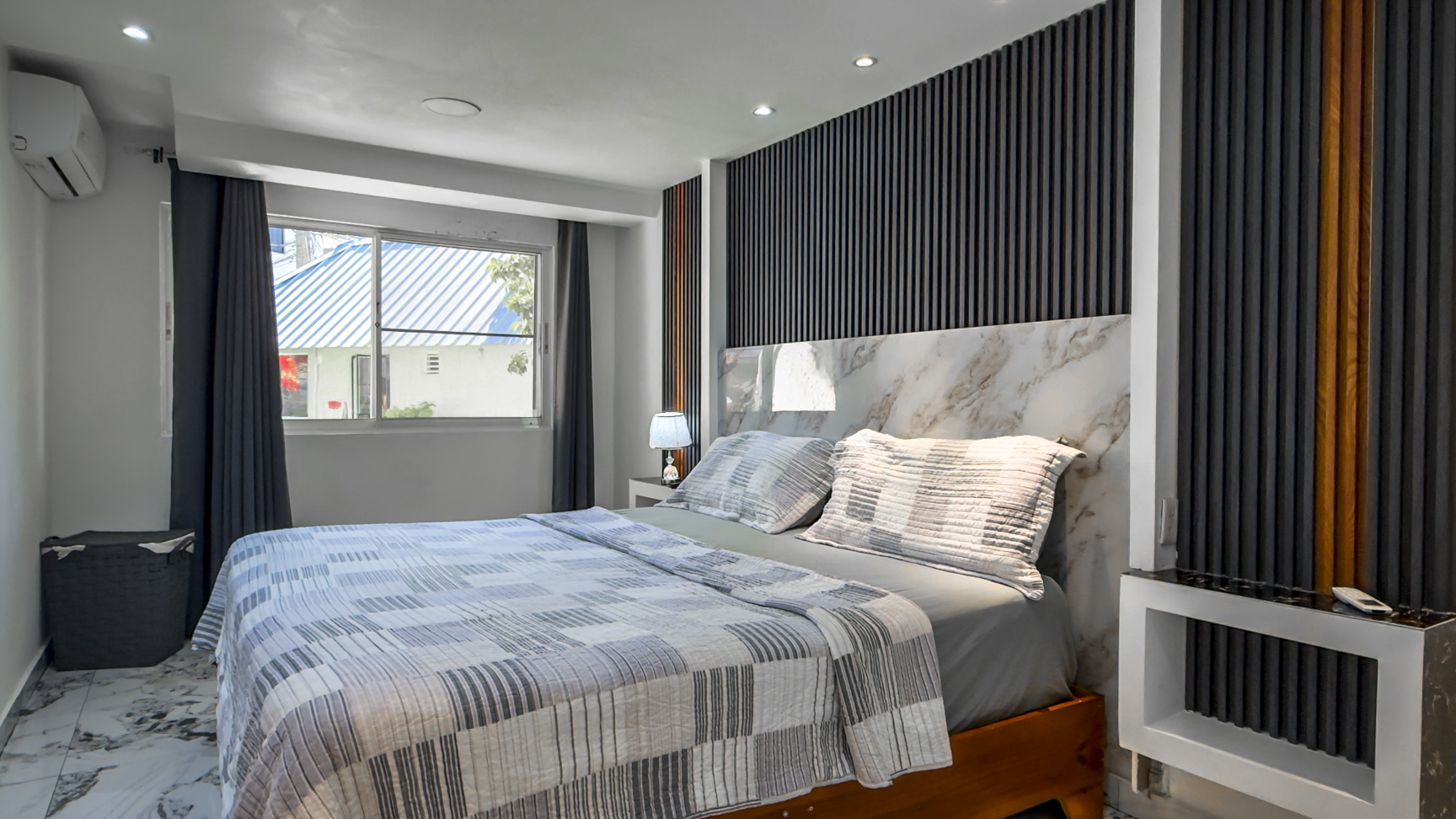Modern bedroom with a king-size bed, marble accents, and a stylish headboard.