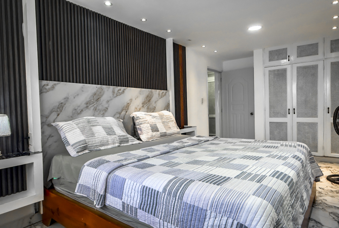 Modern bedroom with a marble headboard, striped bedding, and white wardrobes.