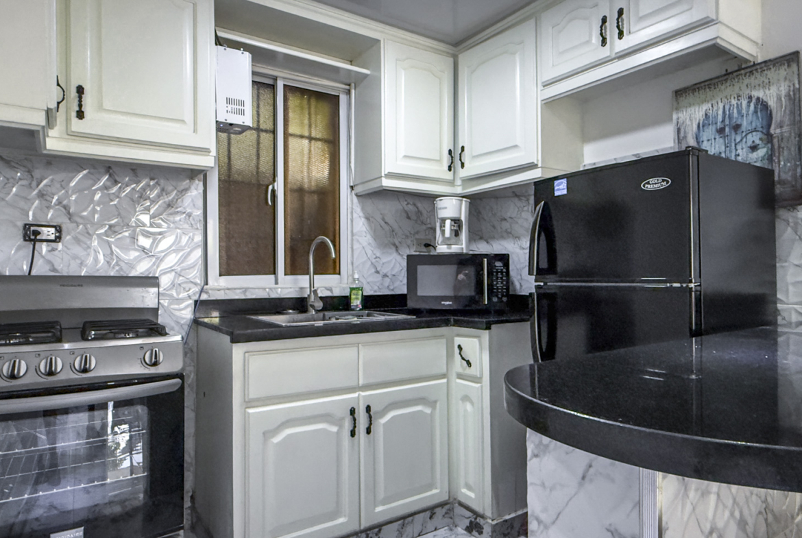 Modern kitchen with white cabinets, black granite countertops, and stainless steel appliances.
