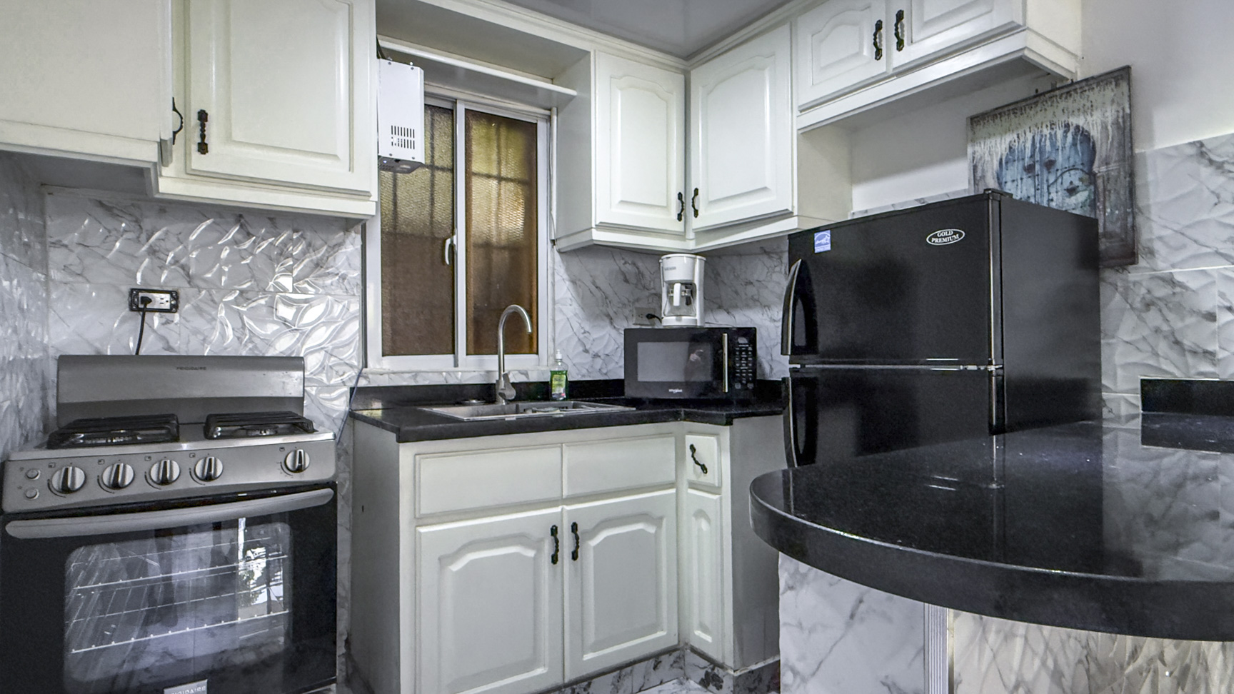 Modern kitchen with white cabinets, black granite countertops, and stainless steel appliances.
