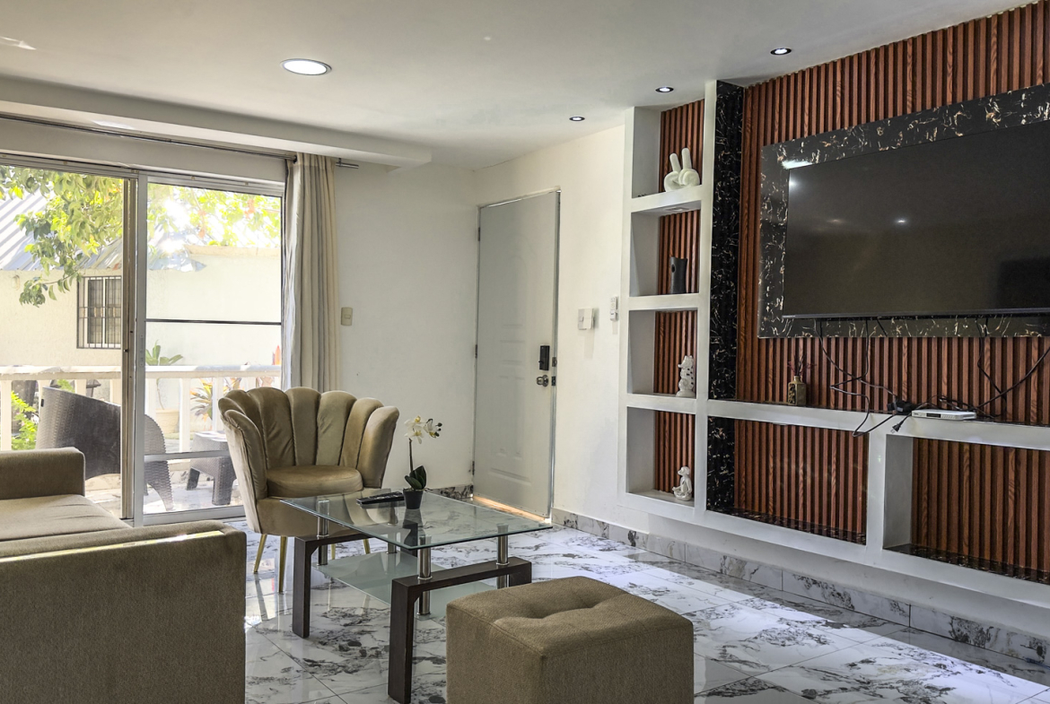 Modern living room with plush seating, glass coffee table, and wall-mounted TV