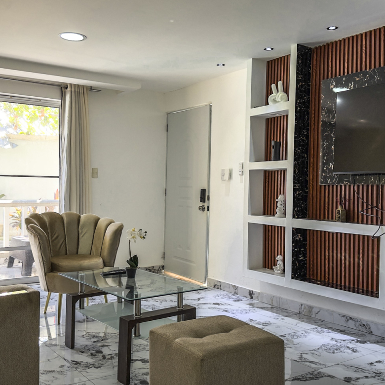 Modern living room with plush seating, glass coffee table, and wall-mounted TV