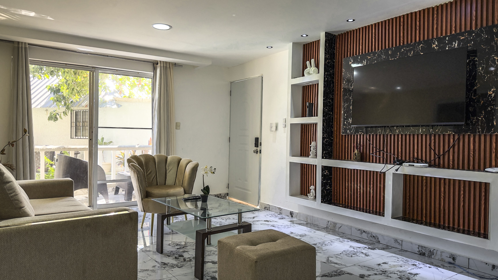 Modern living room with plush seating, glass coffee table, and wall-mounted TV