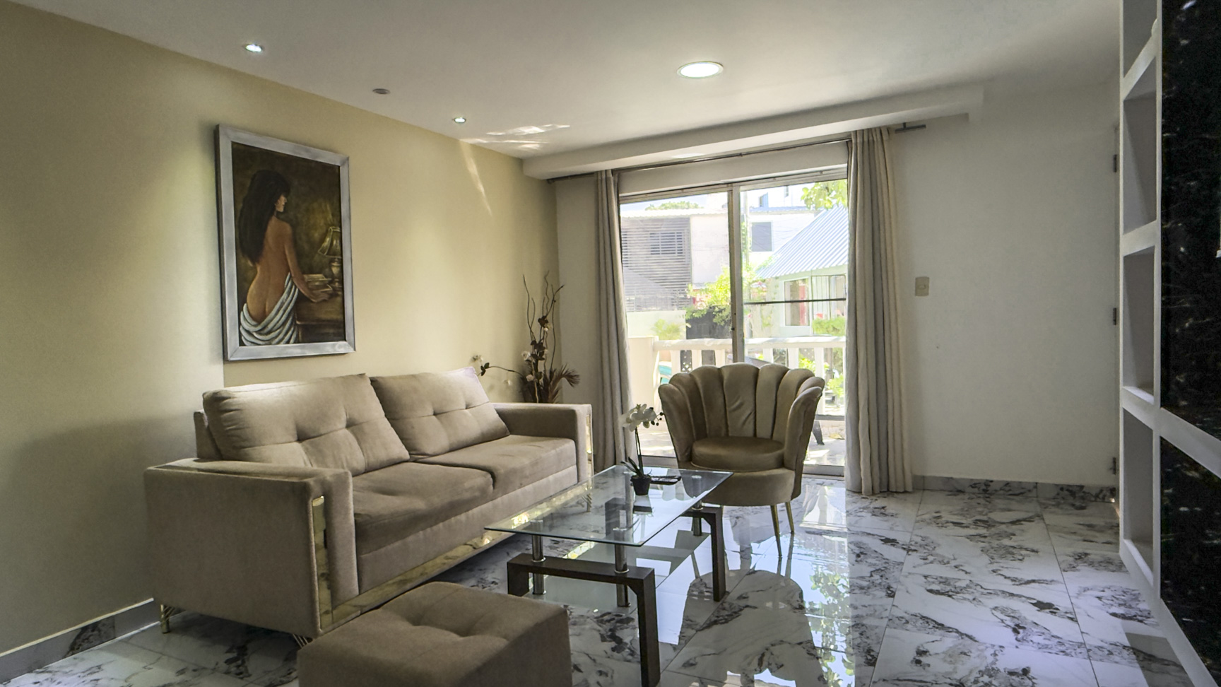 Modern living room with beige sofa, glass coffee table, and art