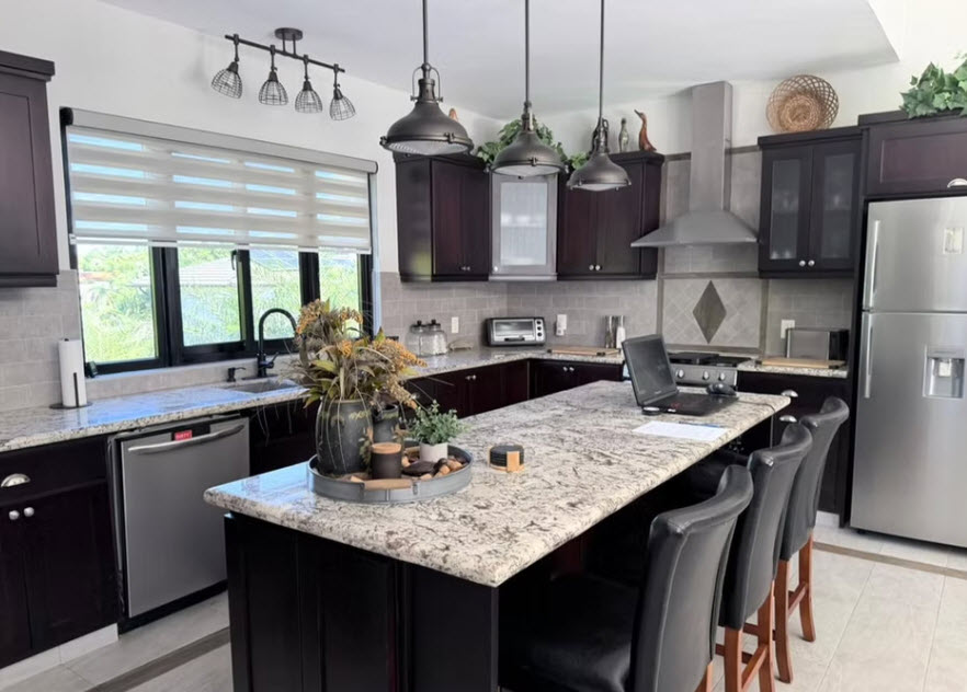 Modern dark wood kitchen with granite island and stainless steel appliances