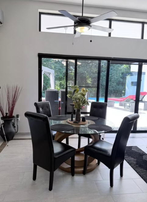 Modern dining room with glass table, black chairs, and view of pool
