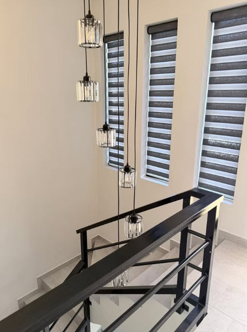 Modern staircase with crystal pendant lights and striped roller blinds