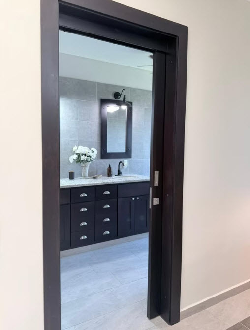 Modern bathroom vanity with dark wood cabinets, granite countertop, and tiled wall.
