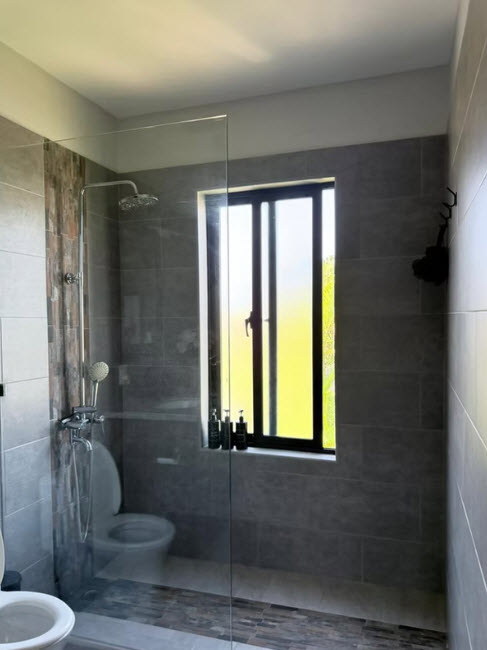 Modern bathroom with walk-in shower, toilet, and window with natural light