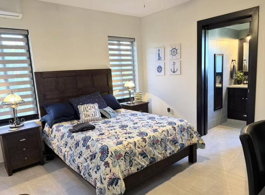 Nautical-themed bedroom with a queen-size bed, dark wood furniture, and adjoining bathroom.