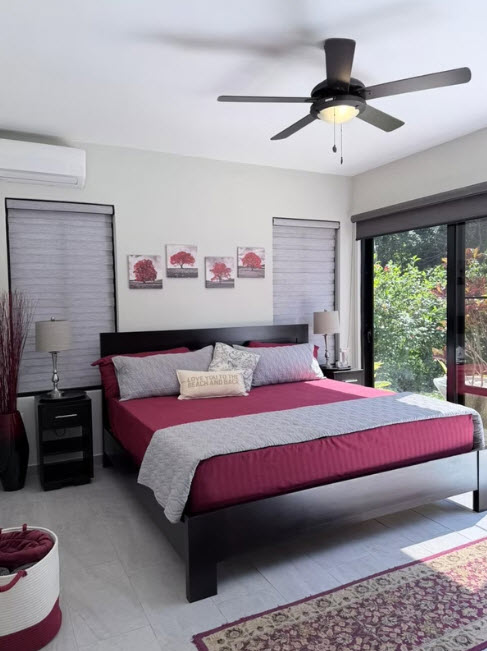 Modern bedroom with a king-size bed, red bedding, and a ceiling fan