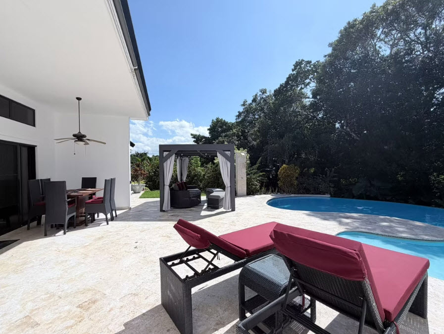 Luxury villa patio with pool, lounge chairs, and outdoor dining area