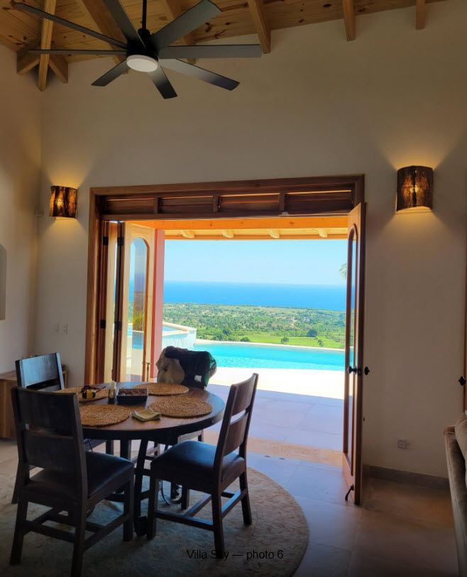 Dining area with ocean view, pool, and tropical landscape at Villa Sky