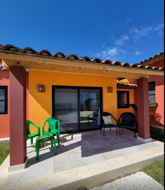 Orange villa patio with green chairs and ocean view