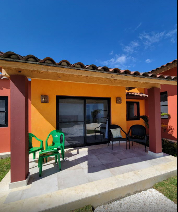 Orange villa patio with green chairs and ocean view